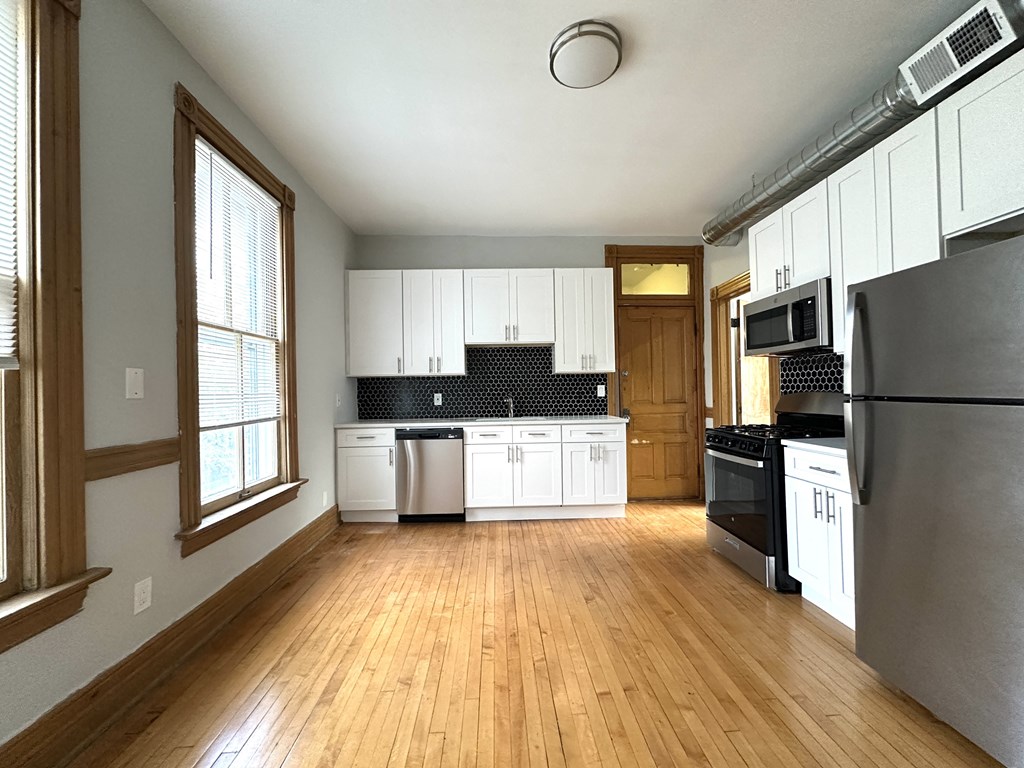 A kitchen with white cabinets and black appliances.