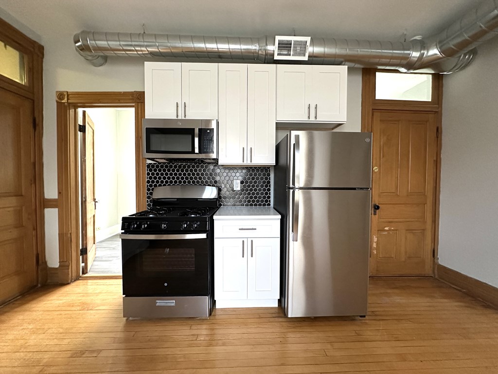 A kitchen with a stainless steel refrigerator and a black stove top oven.