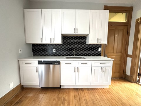 A kitchen with white cabinets and a black and white backsplash.