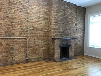 an exposed brick wall in a living room with a hardwood floor and a fireplace