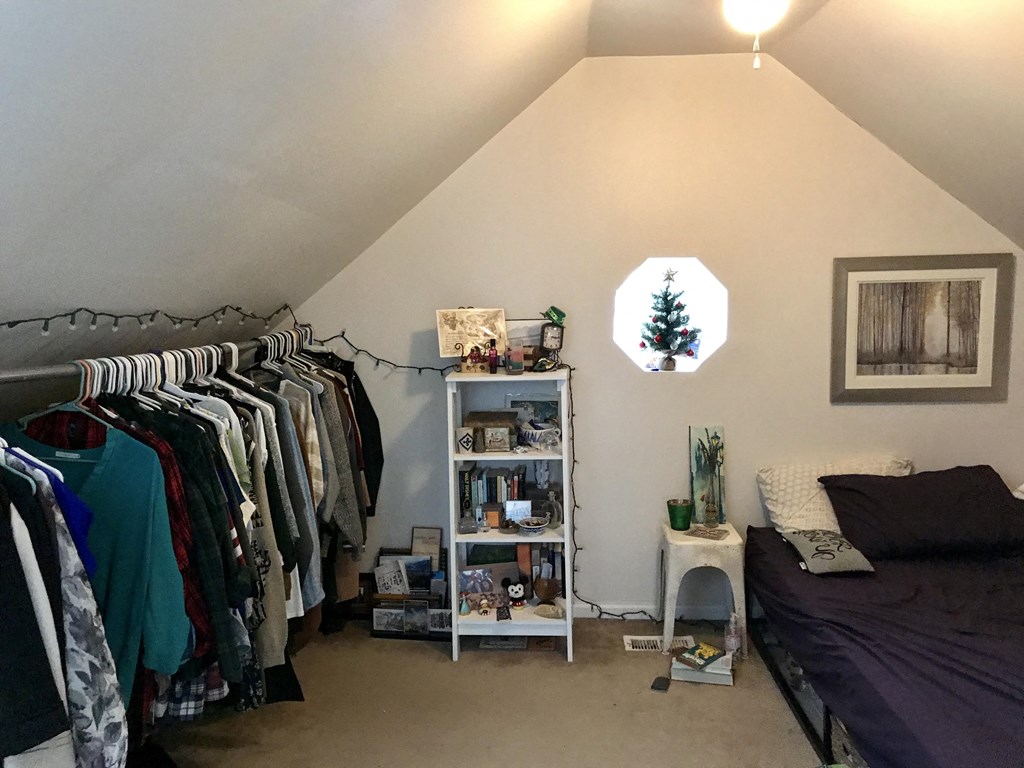 a bedroom with a closet and a bed and a rack of clothes