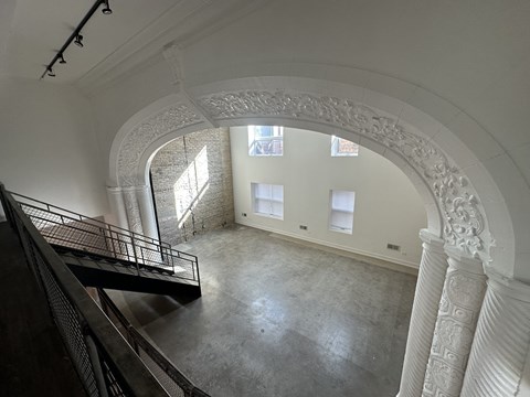 A white arched hallway with a staircase on the left and a window on the right.