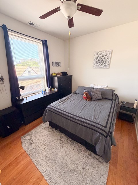 A bedroom with a bed, dresser, and window.