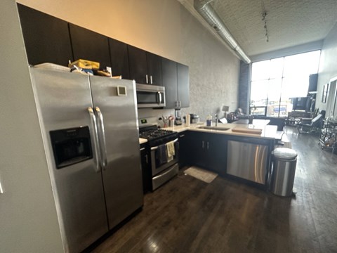 A modern kitchen with a stainless steel refrigerator and black cabinets.