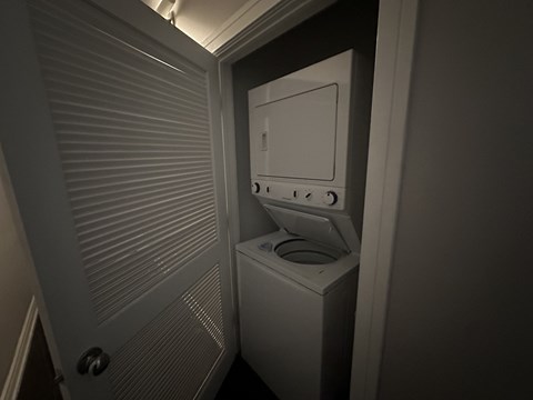 A white washing machine in a small, dark laundry room.