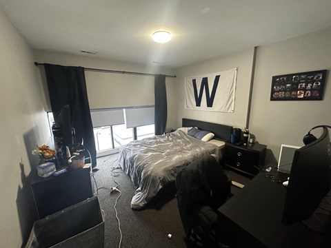 A bedroom with a bed, desk, and chair.
