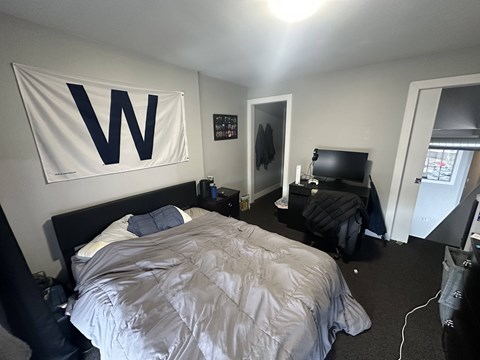 A bedroom with a bed, a dresser, and a wall hanging with the letter W on it.
