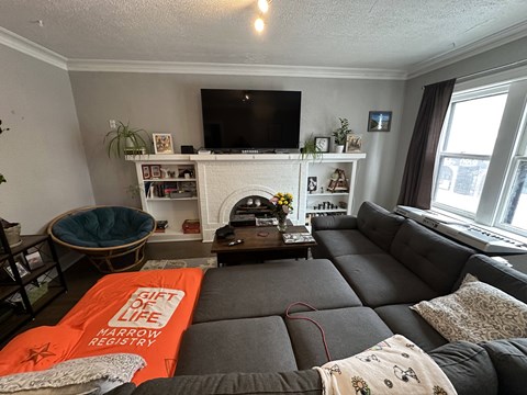 A living room with a grey couch and a television on the wall.