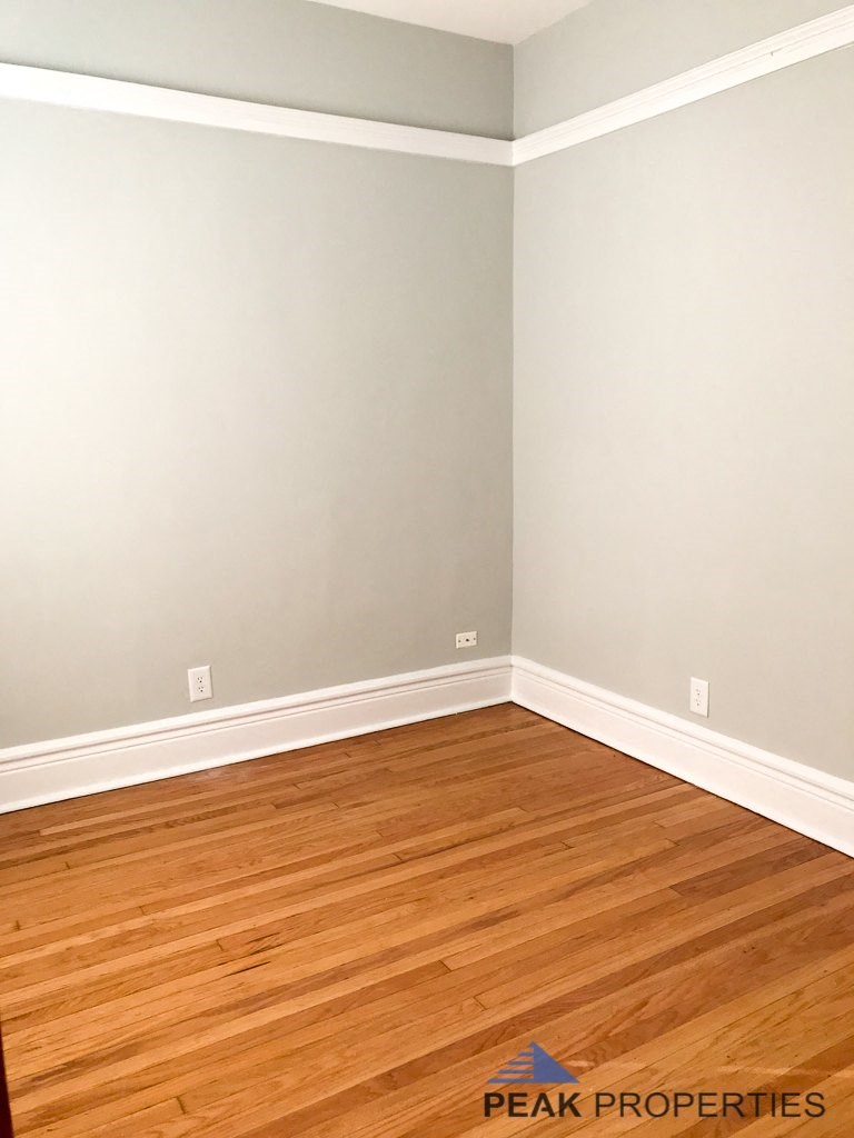 an empty room with wooden floors and gray walls and white trim