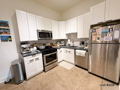 A kitchen with white cabinets and a stainless steel refrigerator.