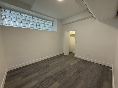 A room with a wooden floor and a window with a grid pattern.