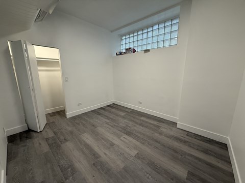 A room with a grey floor and a window with blinds.