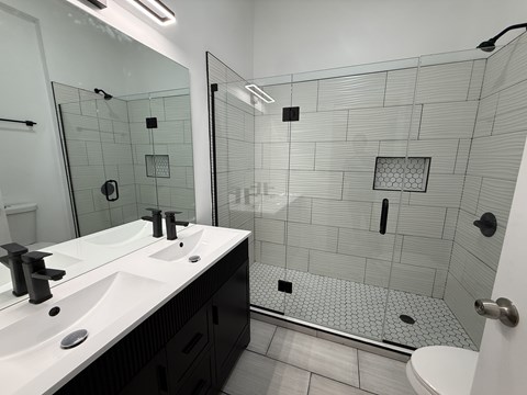 A bathroom with a walk in shower and double sinks.