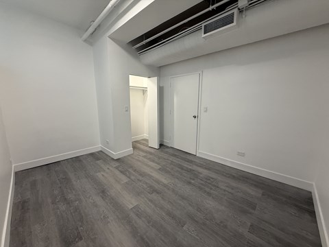 A room with grey flooring and white walls, featuring a door and a window.