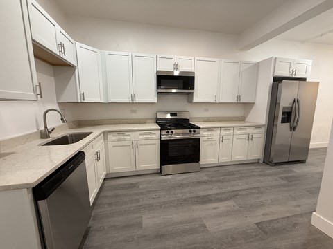 A kitchen with white cabinets and a stainless steel refrigerator.