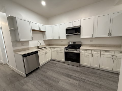 A kitchen with white cabinets and a grey floor.