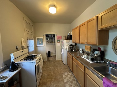 A kitchen with a white stove and wooden cabinets.