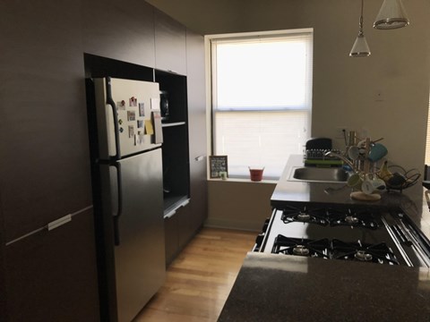 A kitchen with a black fridge and stove top oven.