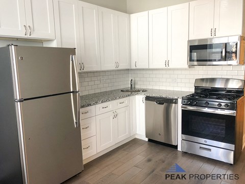 a white kitchen with stainless steel appliances and white cabinets