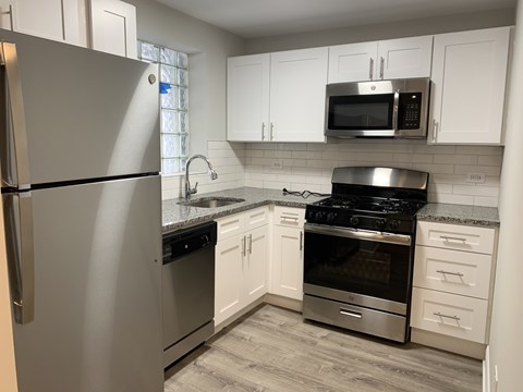 A kitchen with a stainless steel refrigerator, microwave, oven, and stove.