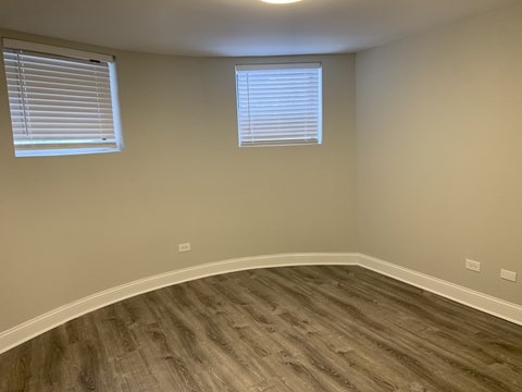 A room with a wooden floor and two windows.
