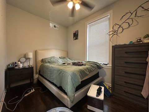 A bedroom with a bed, nightstand, and window.