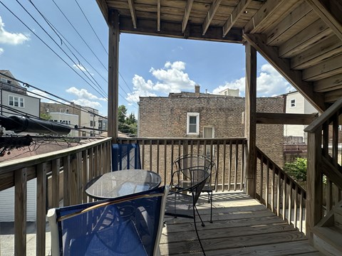 A wooden deck with a table and chairs overlooking a brick building.