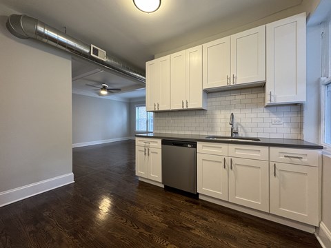 A kitchen with white cabinets and a black countertop.