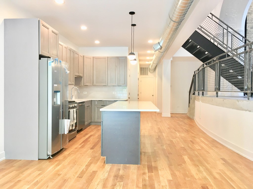 A kitchen with wooden floors and a stainless steel refrigerator.