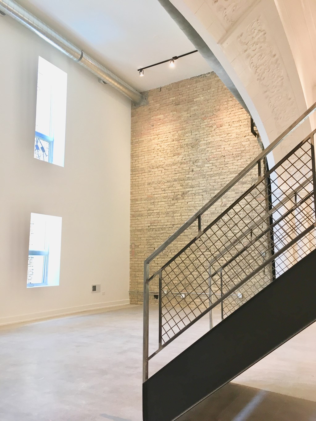 A staircase with a metal railing leads up to a brick wall.