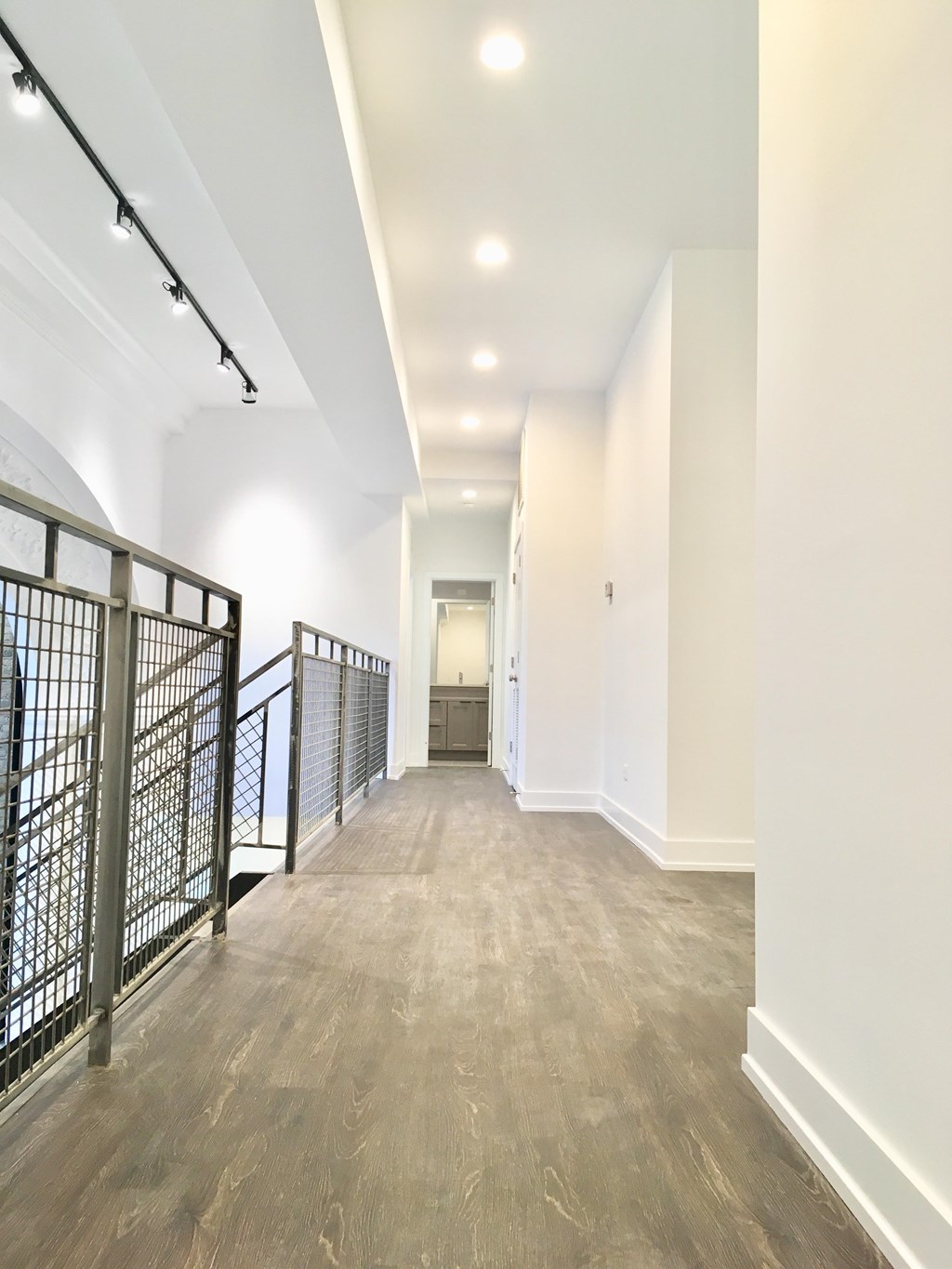 A long hallway with a metal railing on the left side.