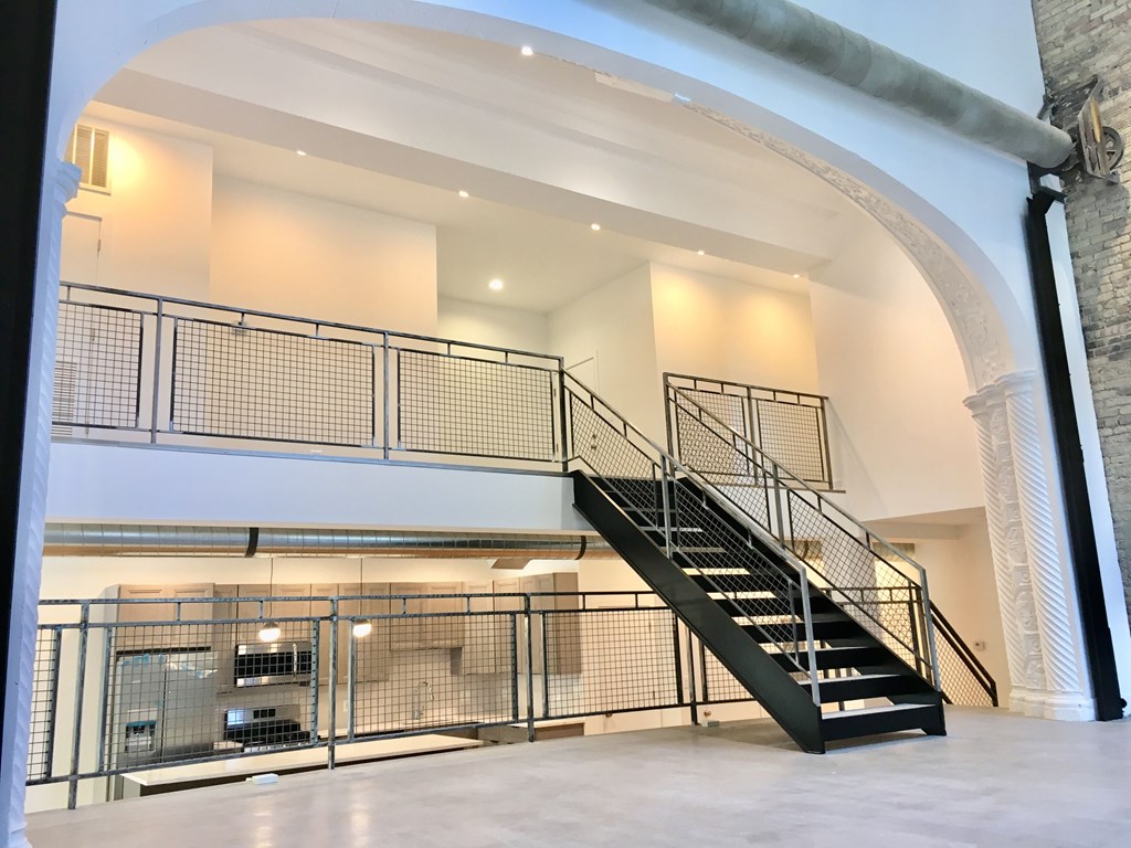 A staircase with a metal railing and a black handrail.
