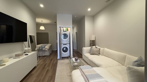 A modern living room with a white sofa and a television on the wall.