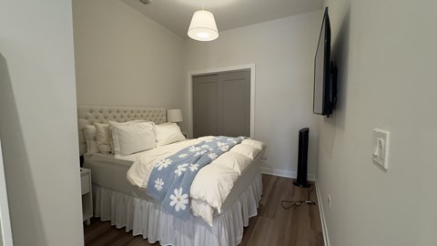 A bedroom with a bed, a television, and a door.