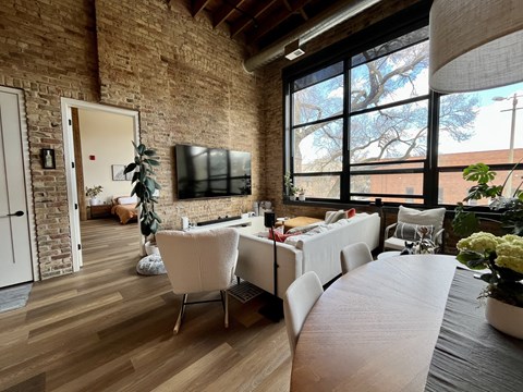 A living room with a white couch and a flat screen TV mounted on the brick wall.