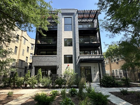 A modern building with a black and white facade is surrounded by greenery.
