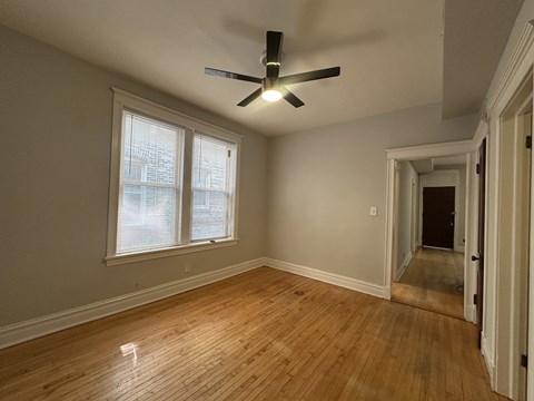 A room with a ceiling fan and wooden flooring.