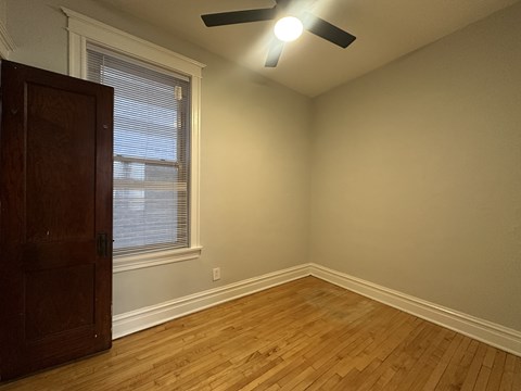 A room with a ceiling fan and a wooden floor.
