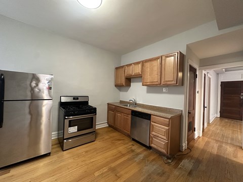 A kitchen with wooden cabinets and a stainless steel refrigerator.