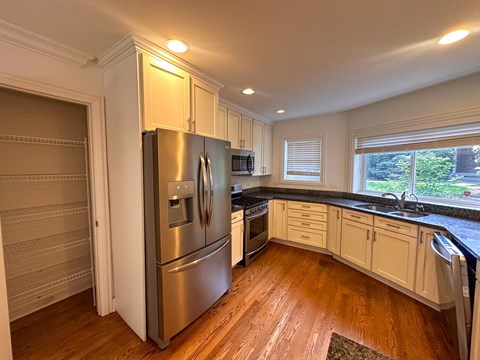 A kitchen with a stainless steel refrigerator and wooden floors.