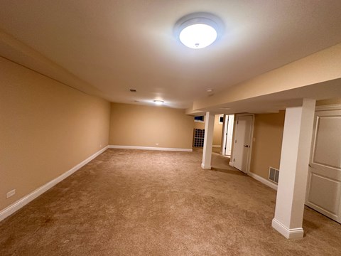 A spacious room with beige carpeting and white columns.
