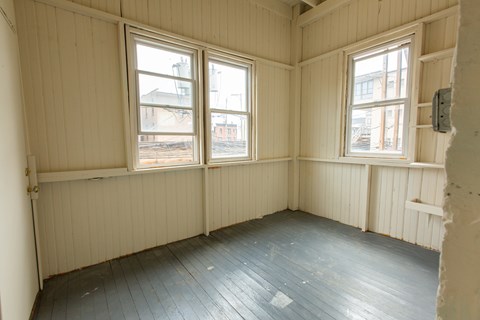A room with wooden floors and two windows.