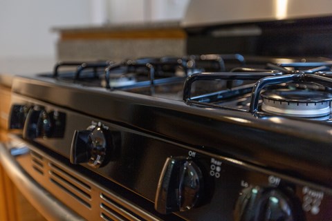 A close up of a black gas stove with four burners and knobs for controls.