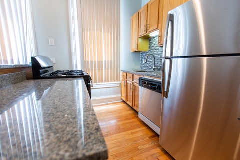 A kitchen with a granite counter top and a stainless steel refrigerator.
