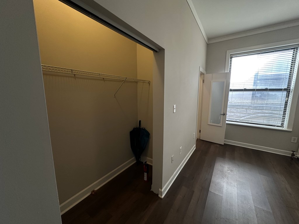 A room with a wooden floor and a window with blinds.