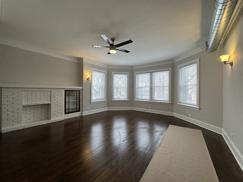 A spacious room with a fireplace and a fan on the ceiling.