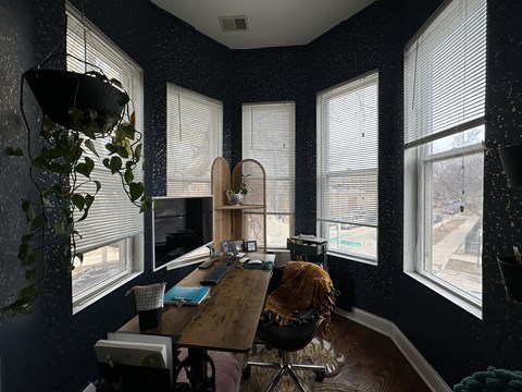 A room with a desk, chair, and a computer monitor.