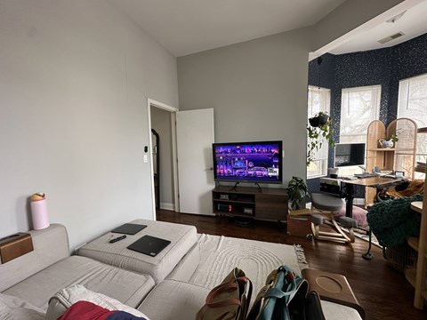 A living room with a grey couch and a television on a wooden stand.
