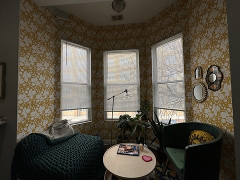 A room with a patterned wallpaper and two windows with blinds.