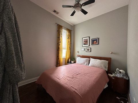 A bedroom with a bed, nightstand, and a ceiling fan.